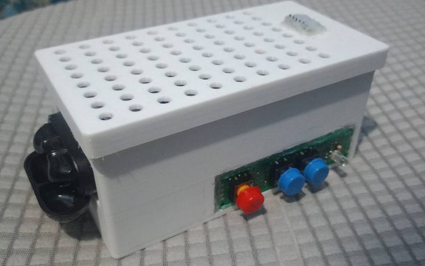 The EarPrompt device: a white 3D-printed enclosure with a perforated lid and a microphone module on top, a front panel with one red and two blue buttons and a status LED, and a Bluetooth earbud case docked on the side.